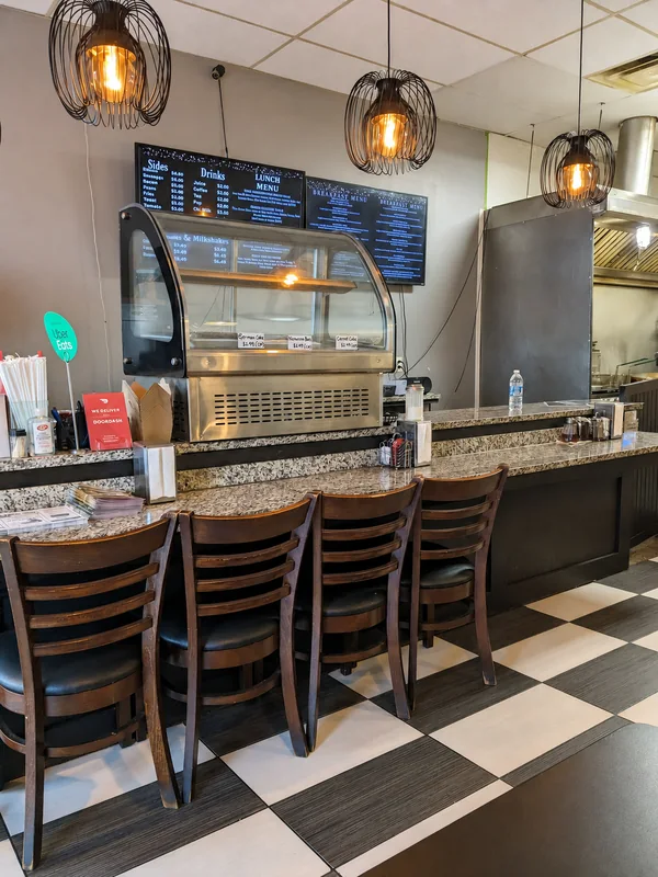 Wooden stools at Nena’s breakfast counter, with hanging lights and a checkerboard floor